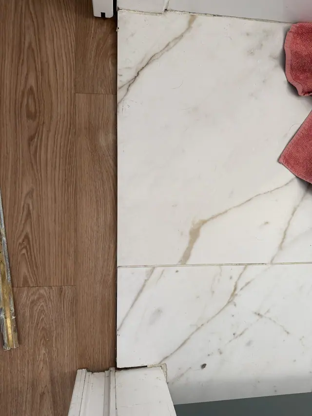 Avant : chant des carreaux visible, carrelage en surépaisseur par rapport au parquet.