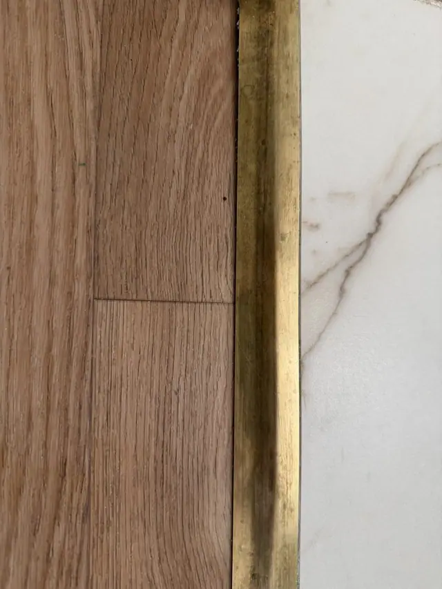 Détail de la barre de seuil posée à fleur du carrelage, transition douce vers le parquet.
