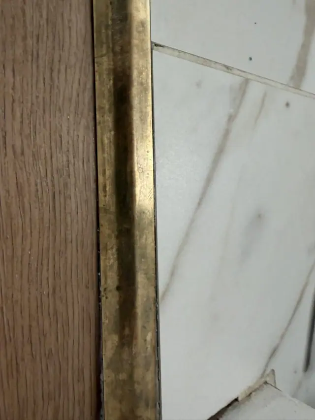 Finition au silicone translucide pour combler les petits vides là où le carrelage était plus haut.