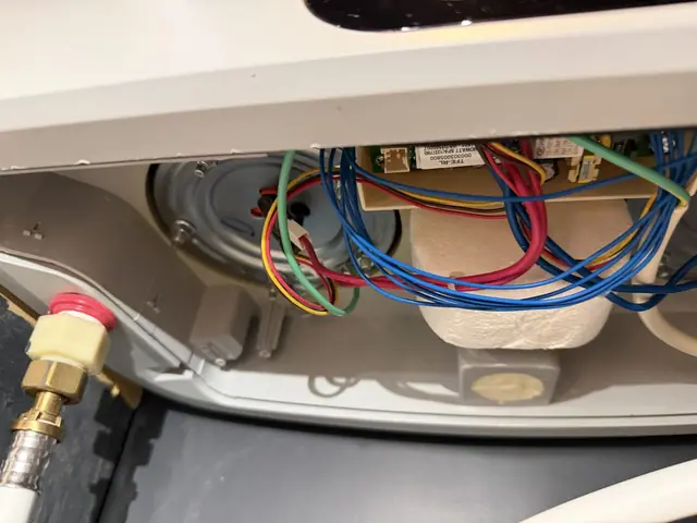 Capot du chauffe-eau Ariston Velis Evo ouvert : carte électronique, câblage et bride de résistance.