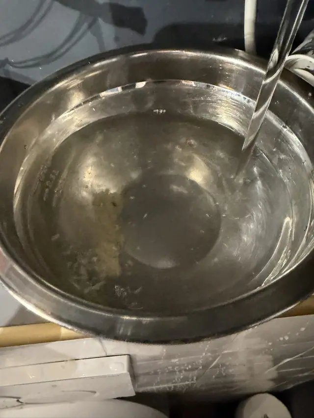 Vidange du ballon dans une bassine : eau chargée de particules de calcaire.