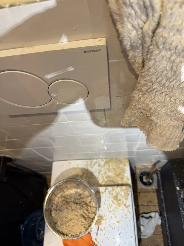 Seau rempli de tartre extrait du ballon d'eau chaude pendant le détartrage.